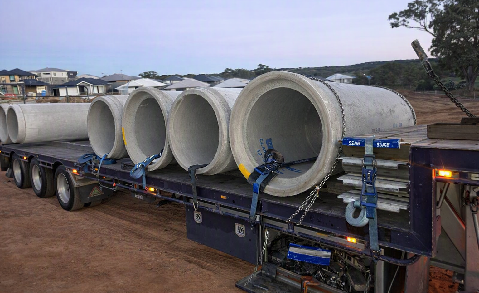 Large concrete pipes secured on flatbed trailer at construction site