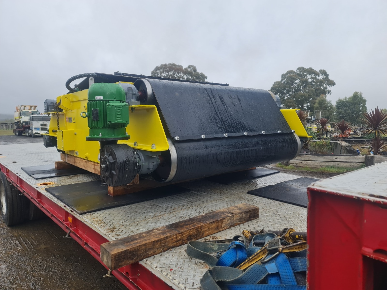Yellow conveyor belt machinery loaded on red flatbed trailer