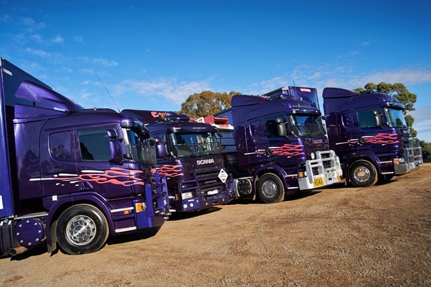 Earls purple Scania fleet lined up on dirt road