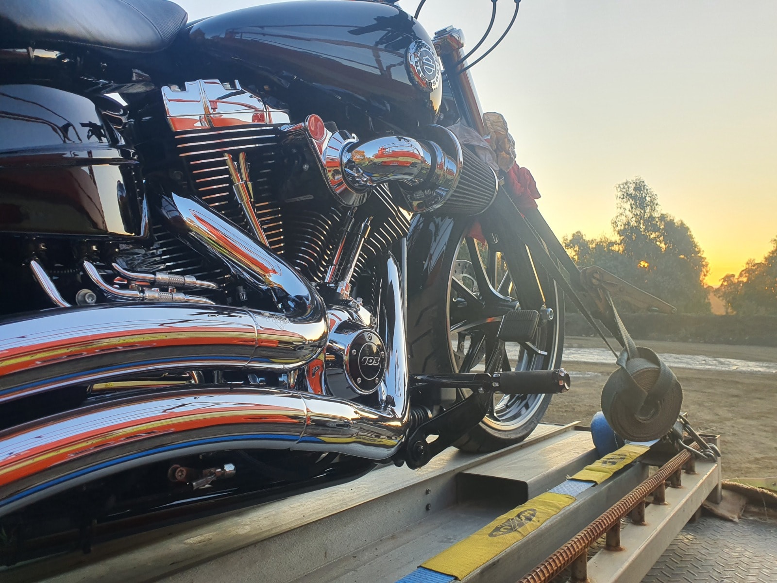 Harley-Davidson motorcycle secured on flatbed at sunset