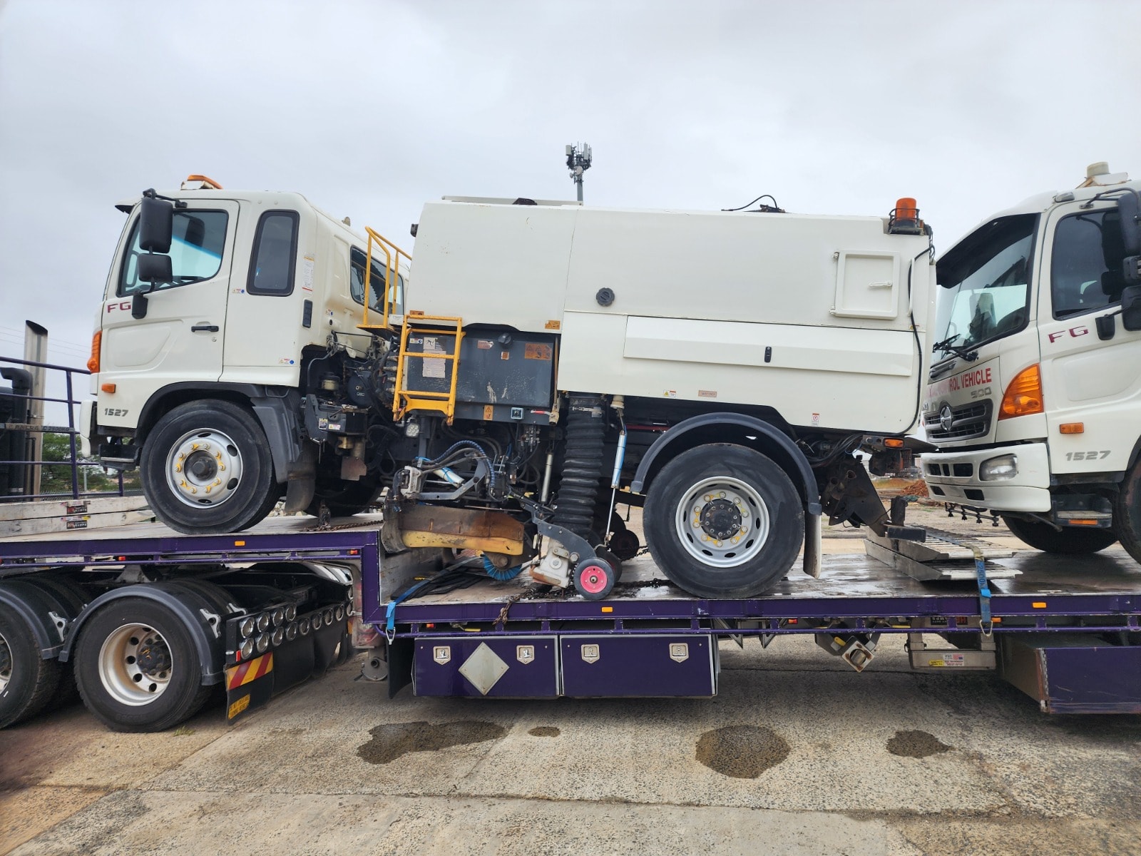 Two Hino FG road sweeper trucks on purple flatbed