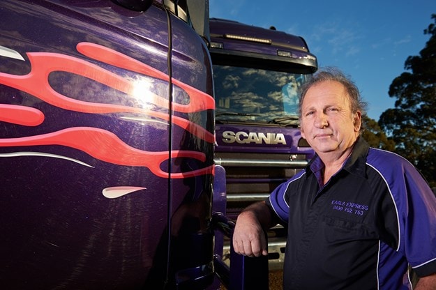 Earls owner standing beside purple Scania truck